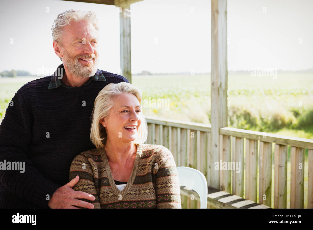 Sorridente coppia senior guardando lontano sulla veranda soleggiata Foto Stock
