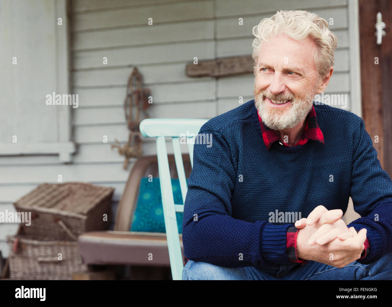 Senior uomo con le mani incrociate che guarda lontano sul patio Foto Stock