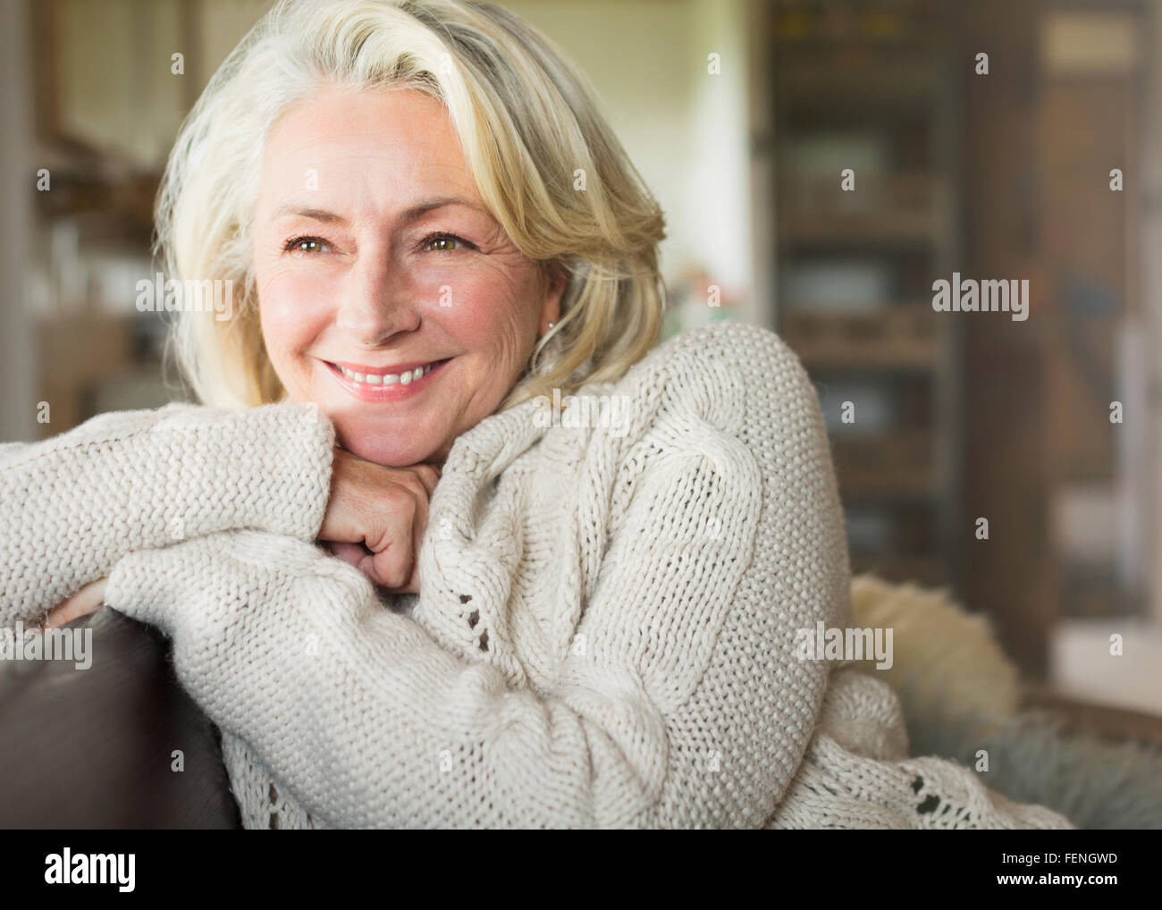 Sorridente donna senior in maglione che guarda lontano Foto Stock