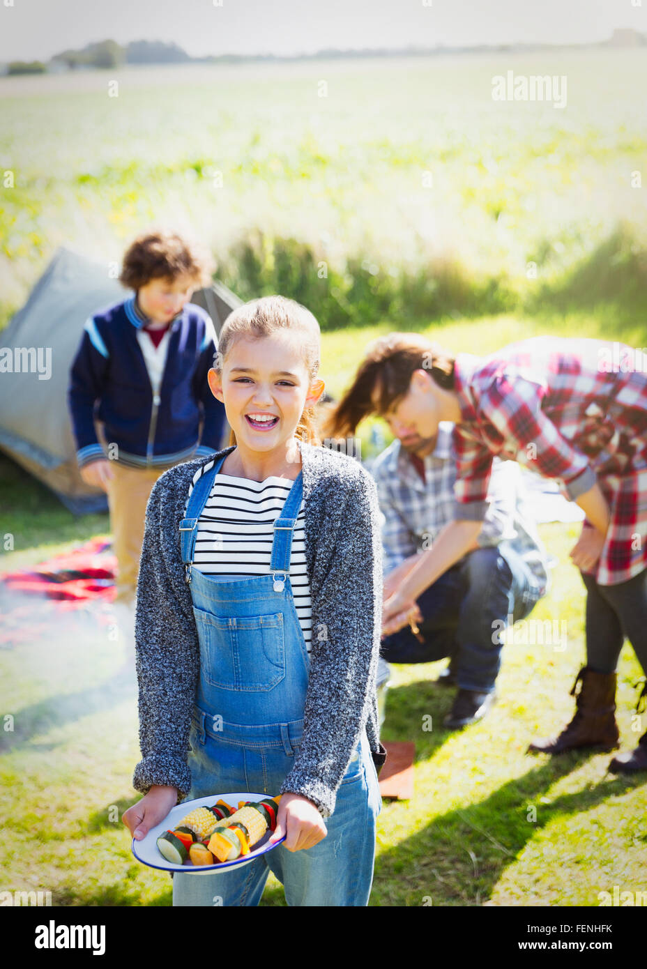 Ritratto sorridente ragazza con gli spiedini di vegetali a sunny campeggio Foto Stock