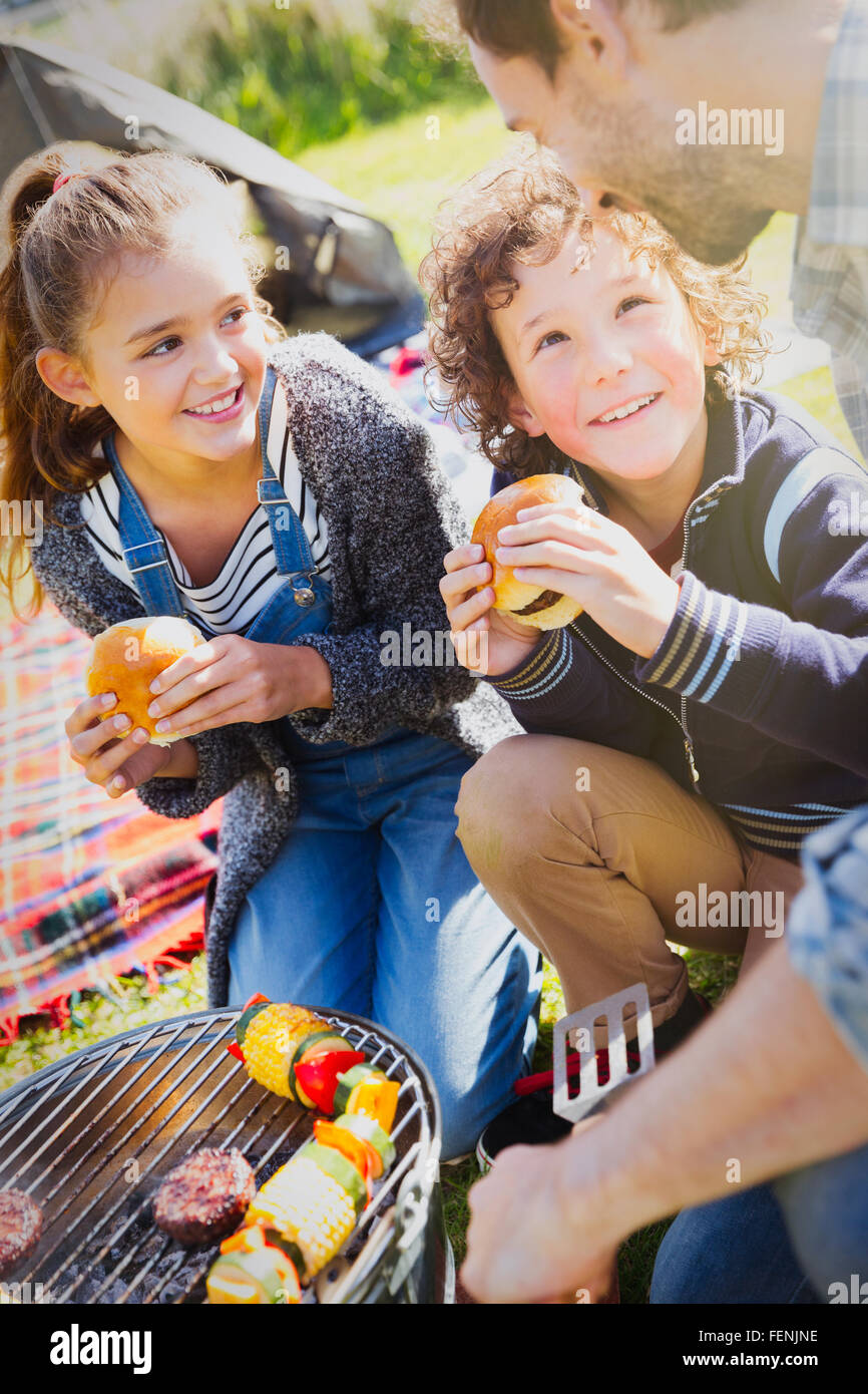 Il padre e i bambini a mangiare hamburger al barbecue grill Foto Stock