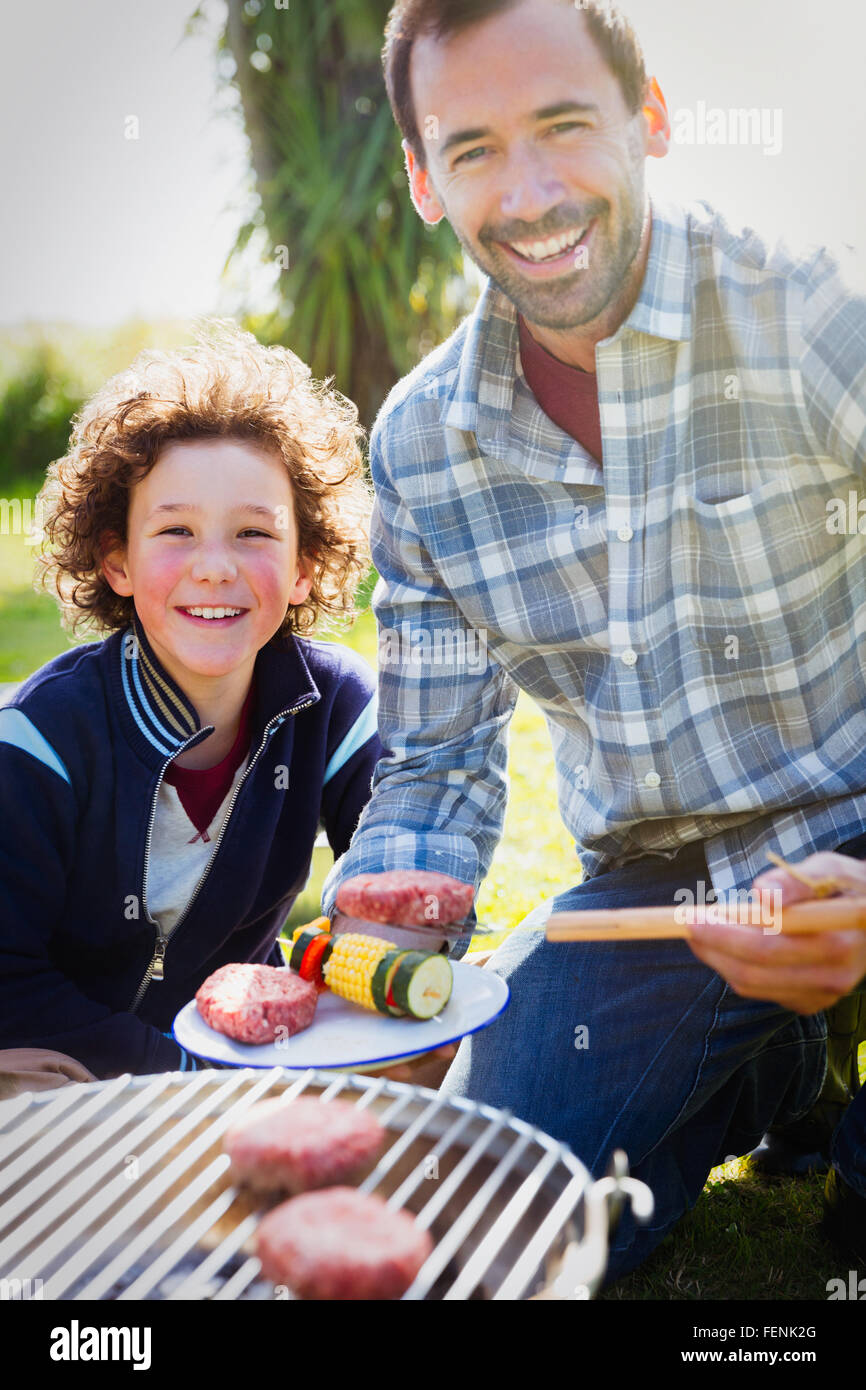 Ritratto sorridente di padre e figlio alla brace Foto Stock