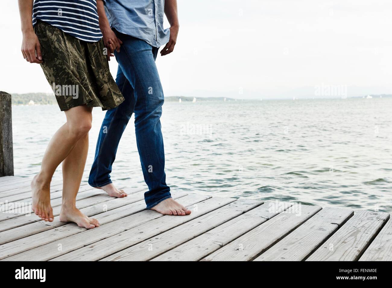 Vista ritagliata della coppia romantica passeggiando sul molo in legno, il lago di Starnberg, Baviera, Germania Foto Stock