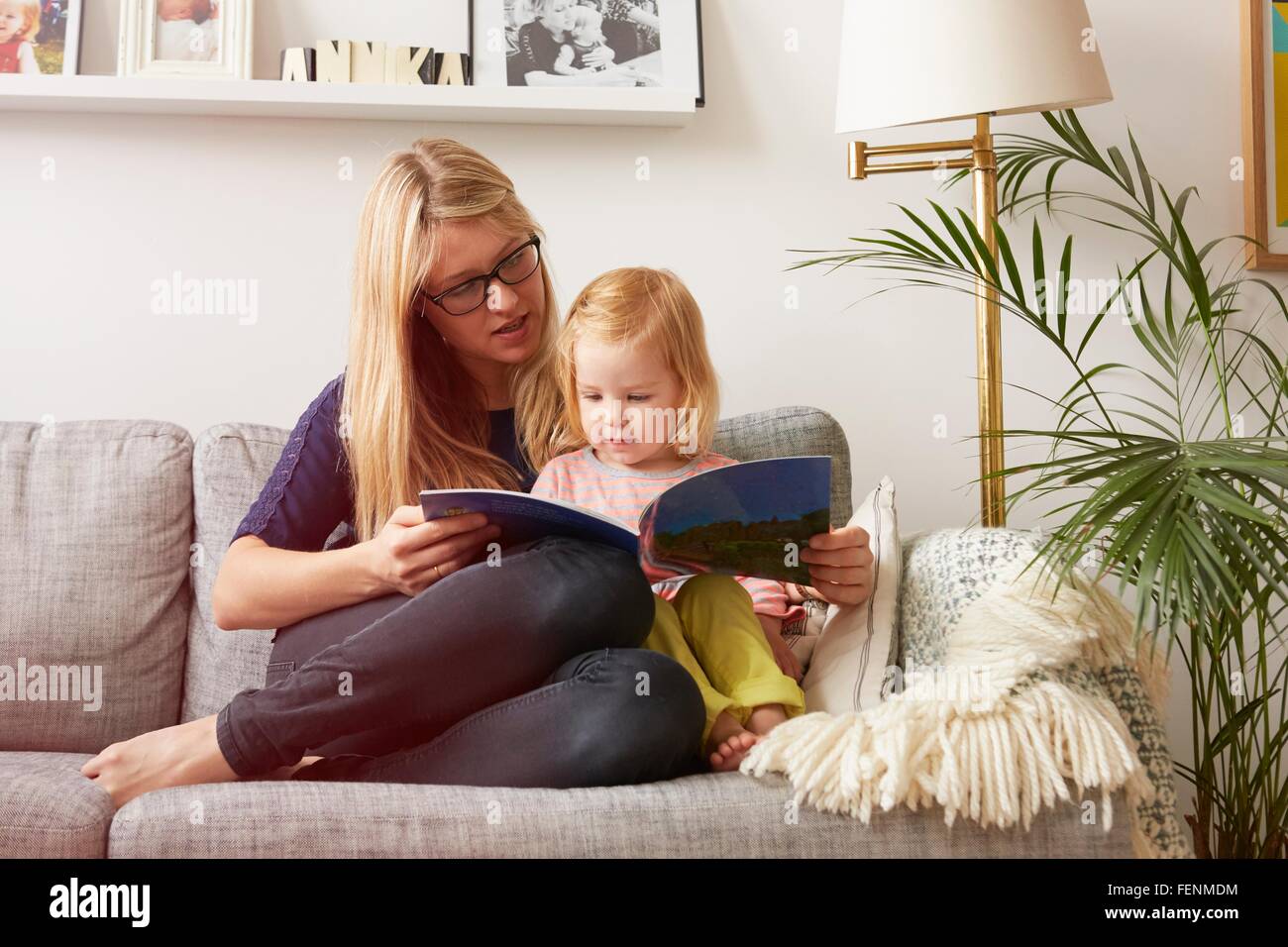 Metà donna adulto e bambino figlia lettura sul divano Foto Stock