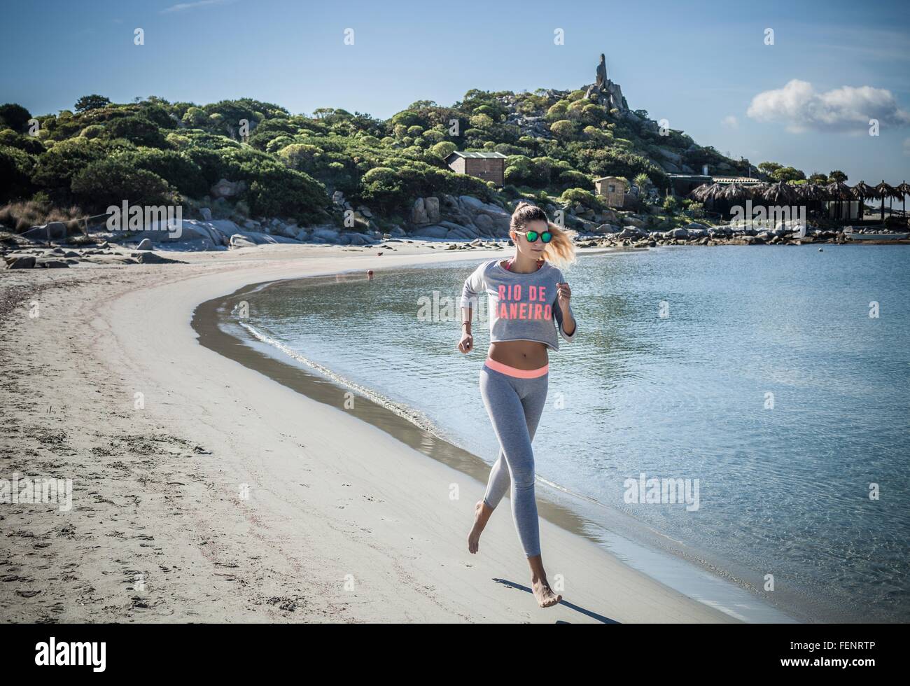 Femminile in esecuzione lungo la spiaggia, a Villasimius, Sardegna, Italia Foto Stock