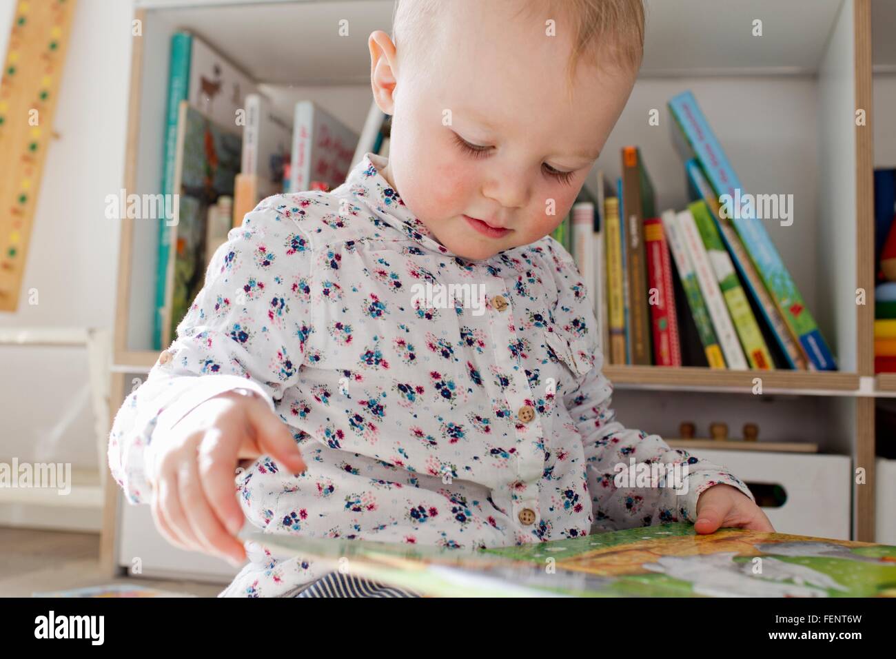 Femmina lettura toddler libro in sala giochi Foto Stock