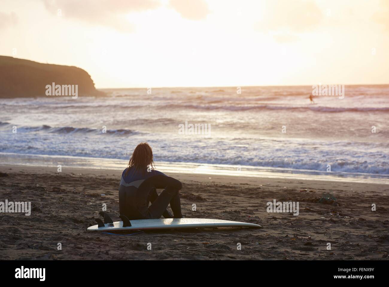 Giovane maschio surfer seduto a guardare fuori dalla spiaggia, Devon,  Inghilterra, Regno Unito Foto stock - Alamy