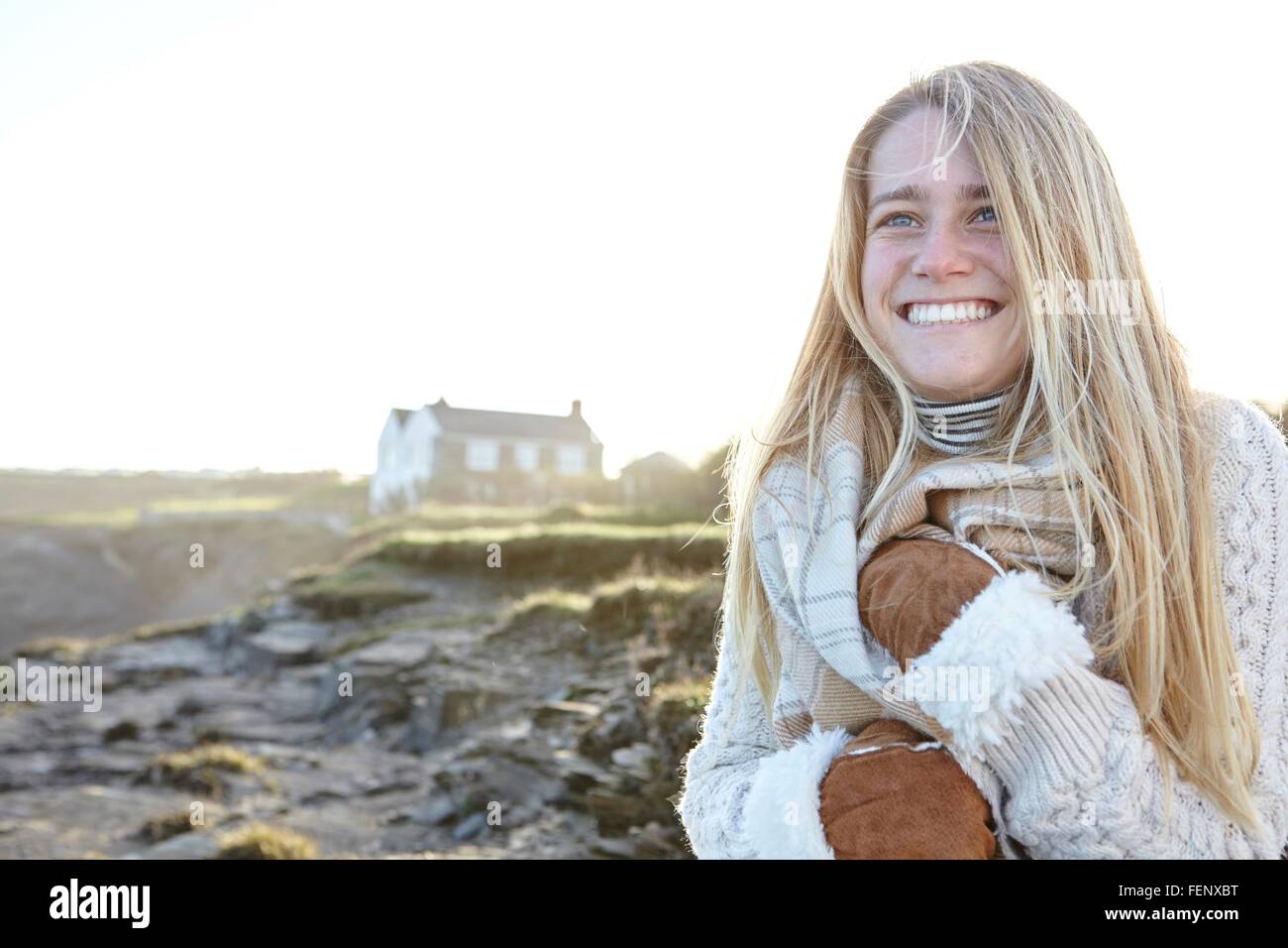 Felice giovane donna confezionamento in sciarpa a beach, Constantine Bay, Cornwall, Regno Unito Foto Stock
