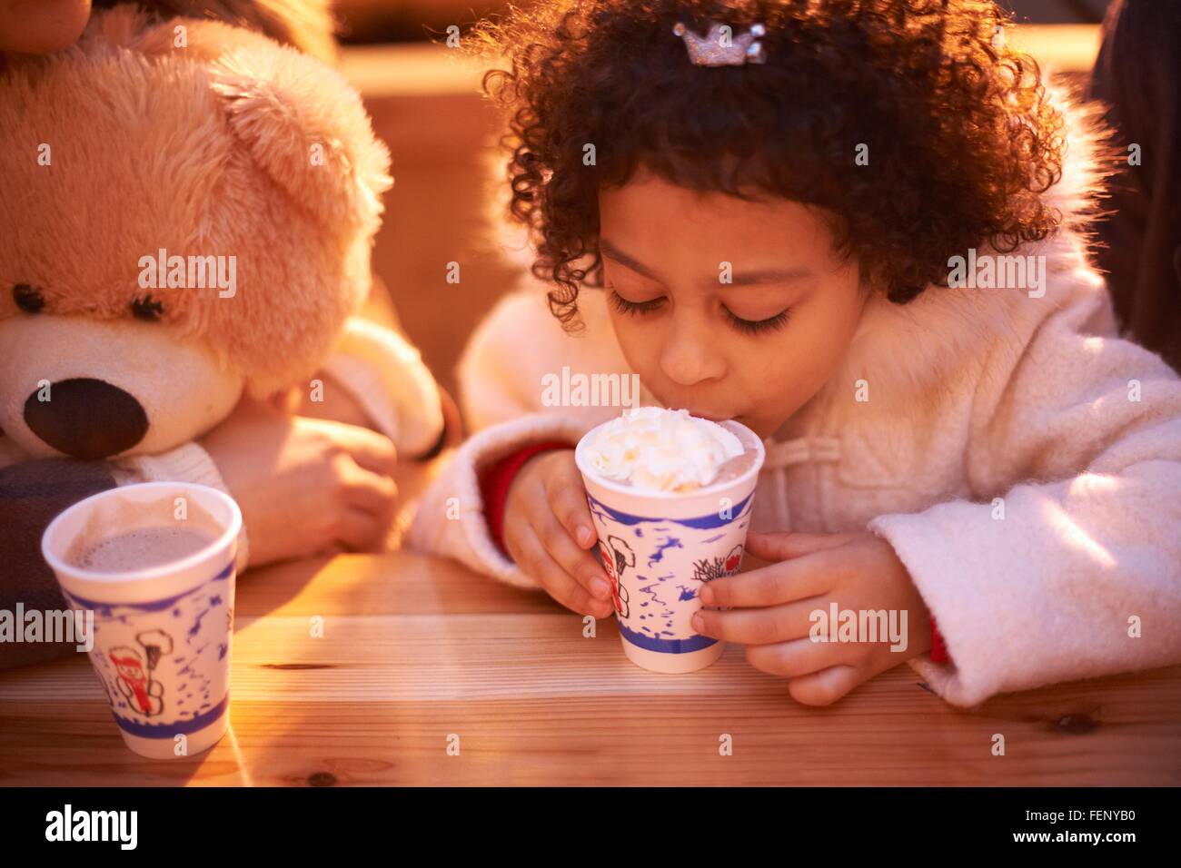 Angolo di Alta Vista della ragazza e orsacchiotto bere cioccolata calda, guardando verso il basso Foto Stock