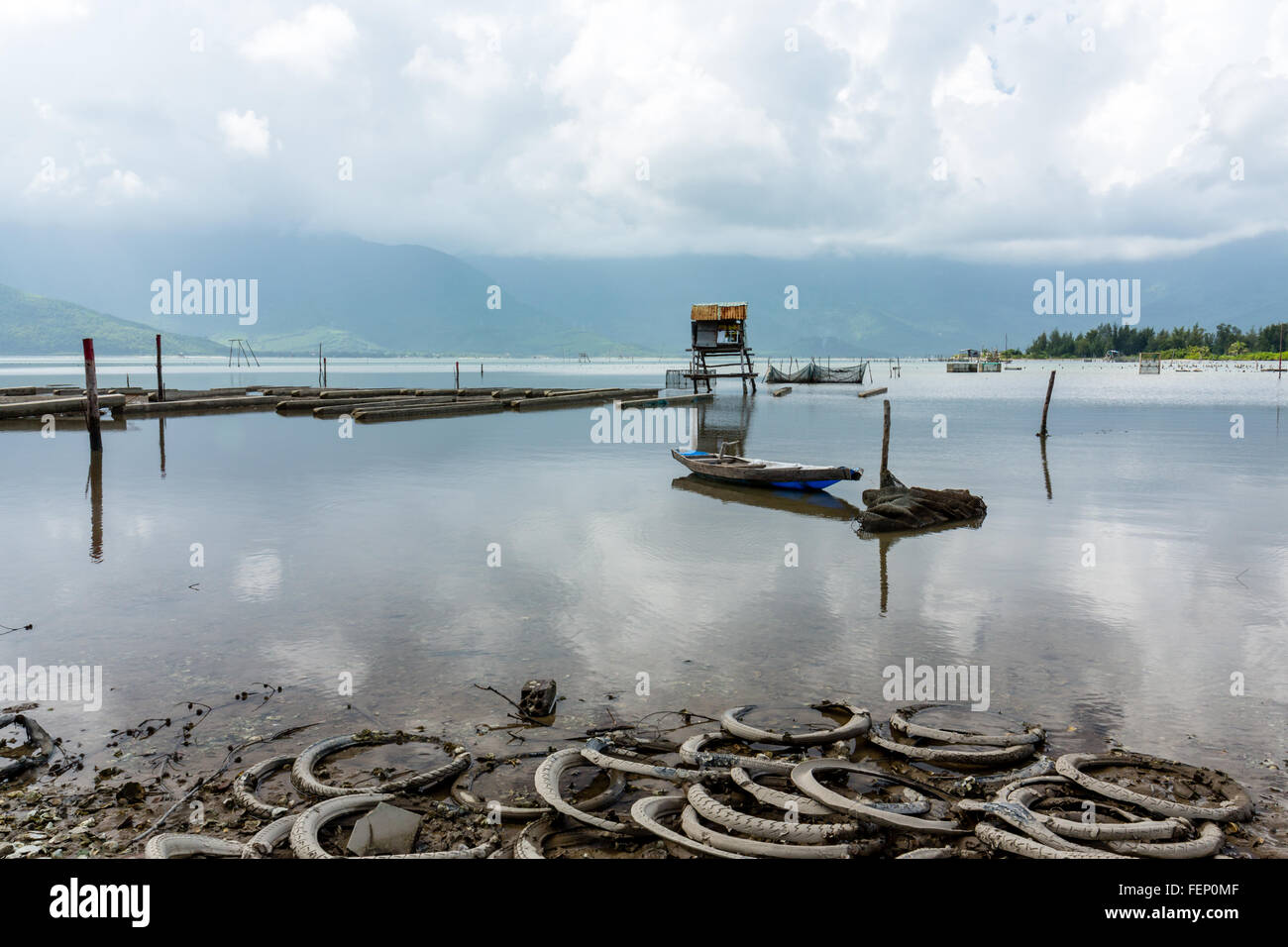 Vista del lago per la pesca sportiva con pneumatici, barca e stilt capanna in Vietnam Foto Stock