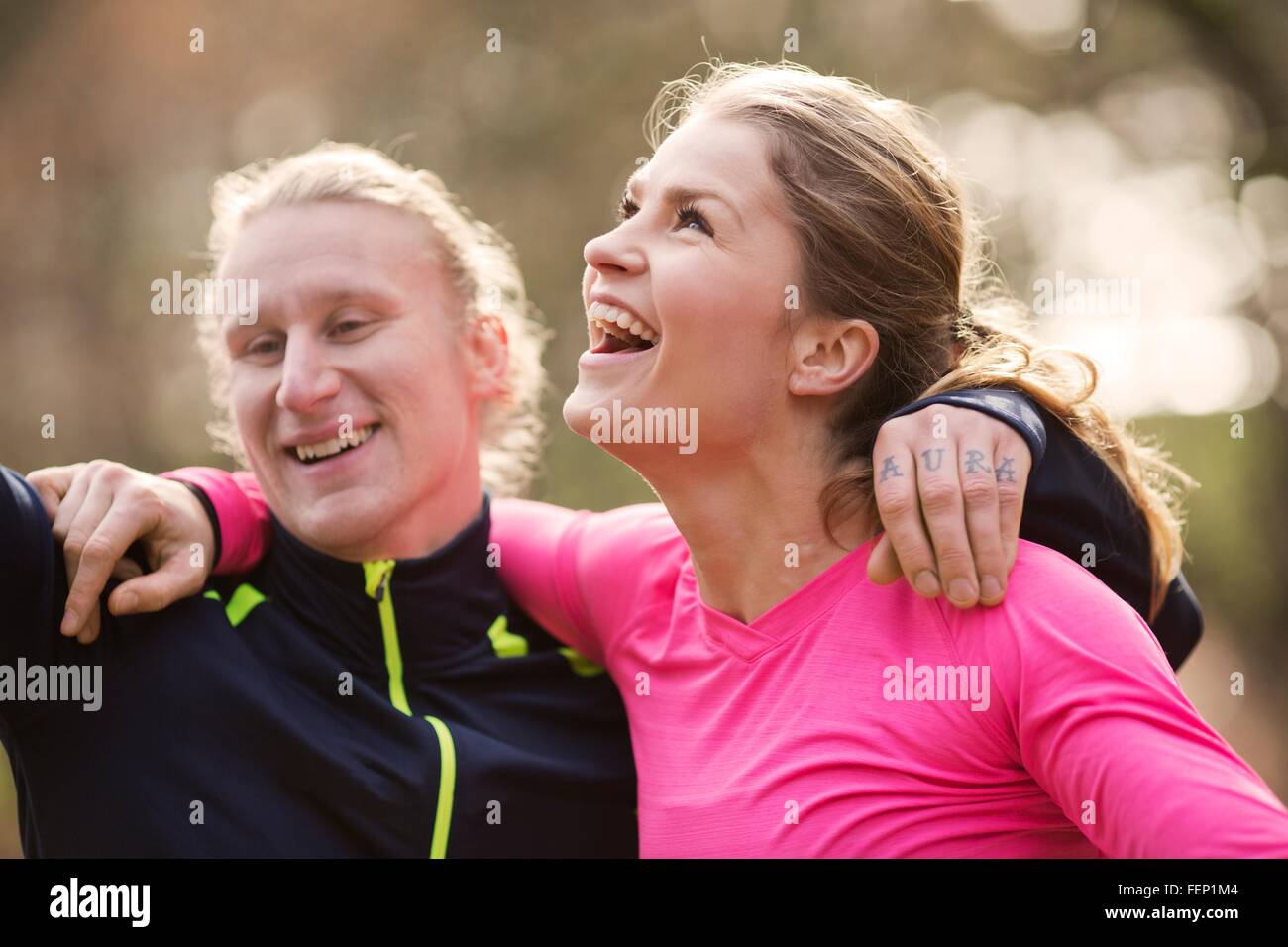 La testa e le spalle del giovane di indossare abbigliamento sportivo bracci intorno a ogni altro che guarda lontano sorridente Foto Stock