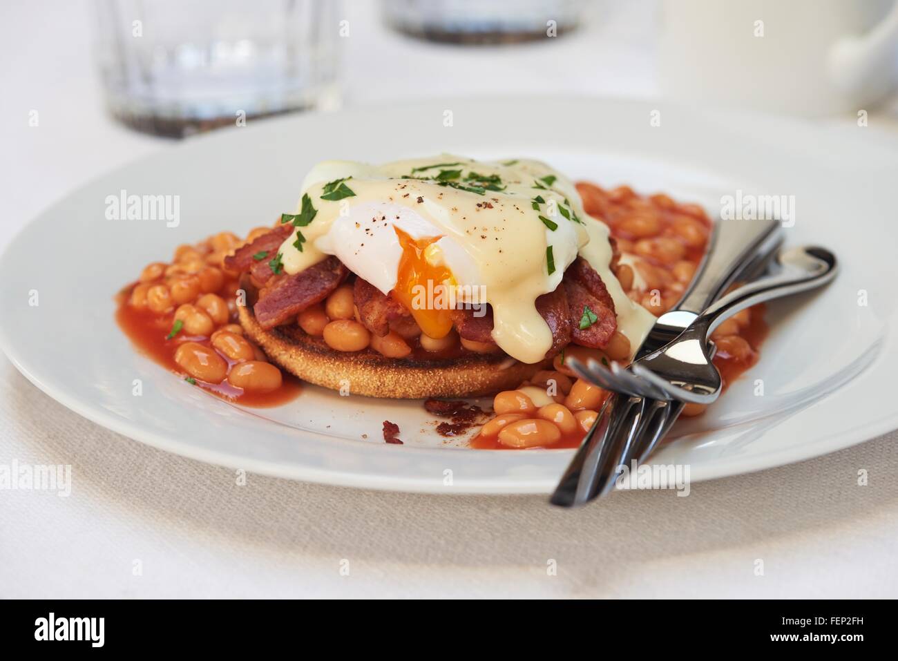Uovo affogato, fagioli e pancetta con salsa olandese sui muffin inglese Foto Stock