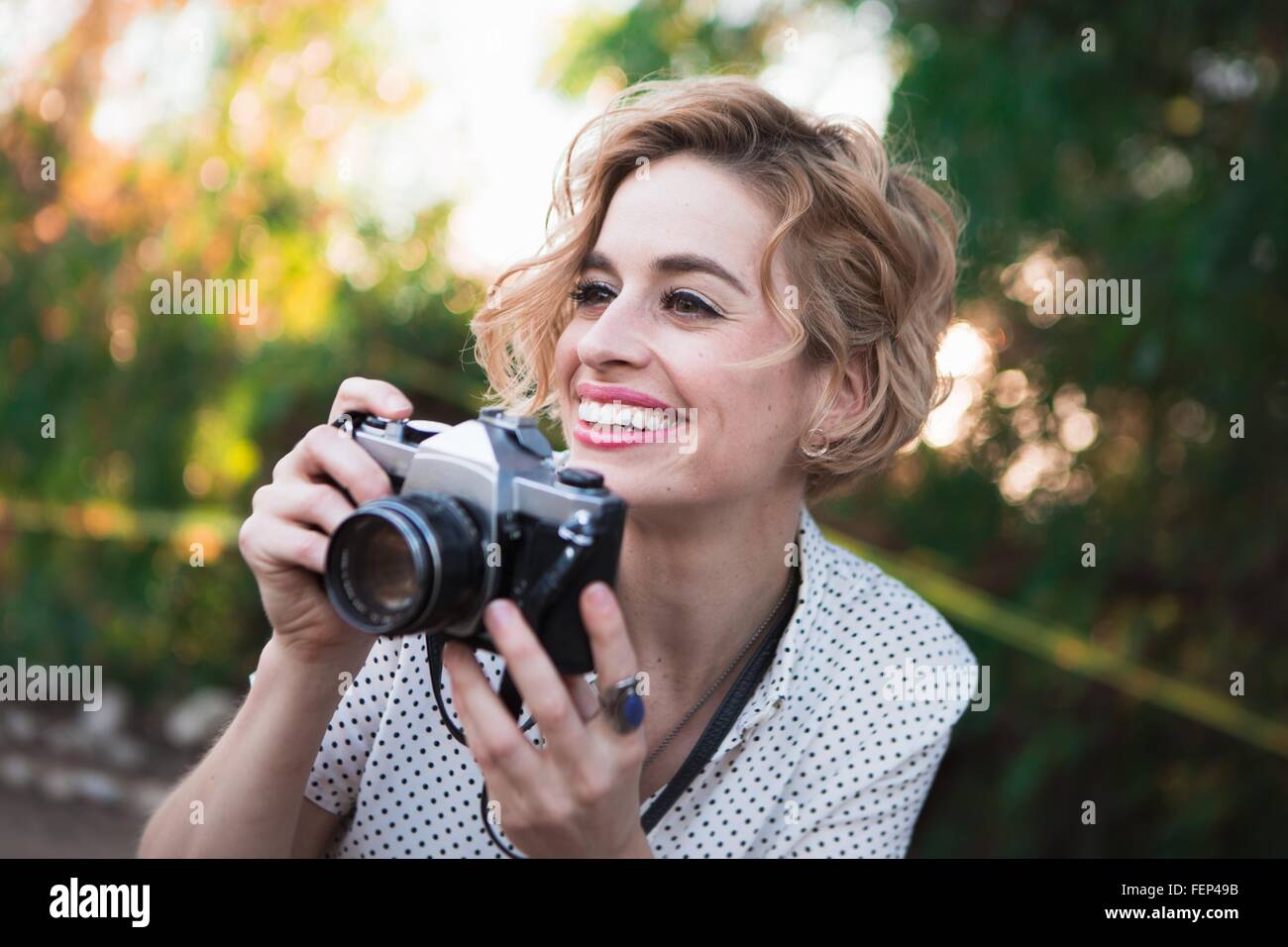 Metà donna adulta prendendo fotografie, all'aperto, sorridente Foto Stock