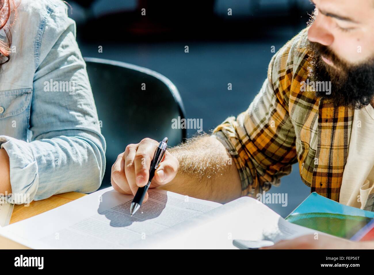 Ritagliato shot di maschio e femmina studenti del college con lettura a scrivania Foto Stock
