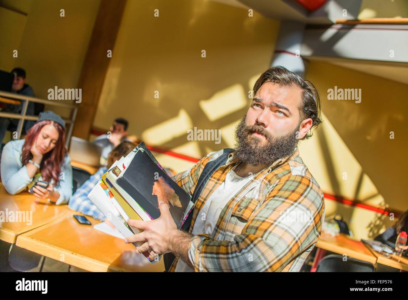 Ritratto di maschio adulto studente di college il trasporto di libri in aula Foto Stock