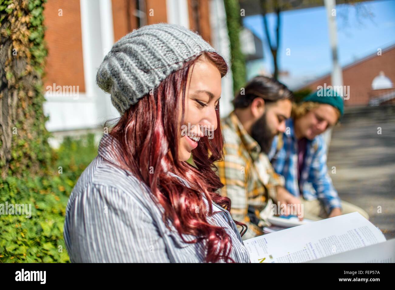 Adulto studenti universitari la lettura di libri sulla parete del campus Foto Stock