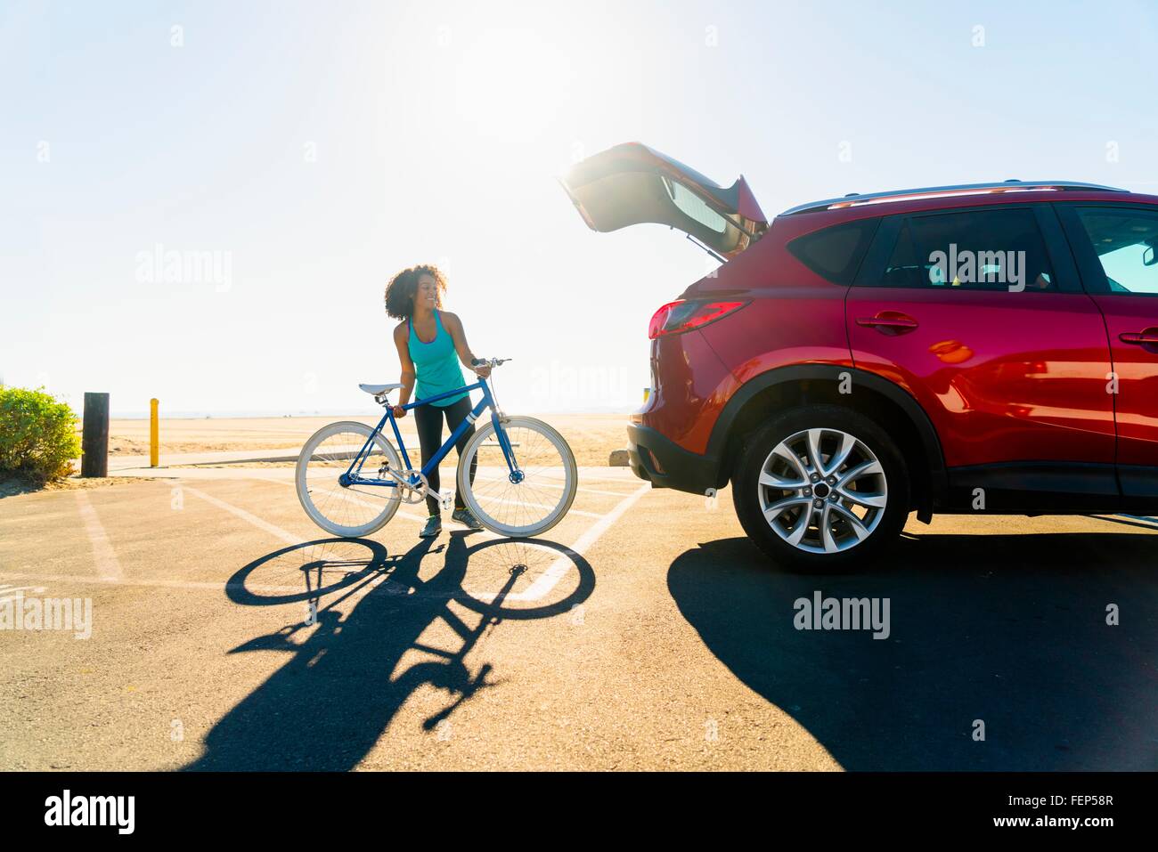 Metà donna adulta mettendo bicicletta nel bagagliaio della vettura Foto Stock