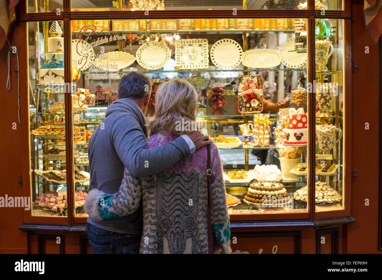 Vista posteriore della romantica coppia matura al negozio di dolci finestra, Maiorca, SPAGNA Foto Stock