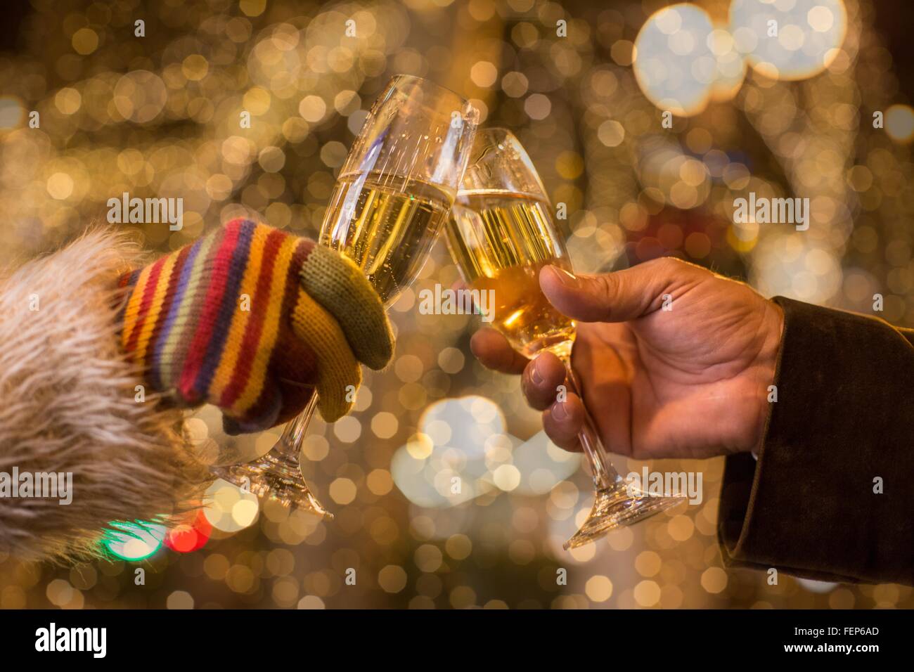 Close up di coppie mani fare un brindisi con champagne nella parte anteriore delle luci di Natale Foto Stock
