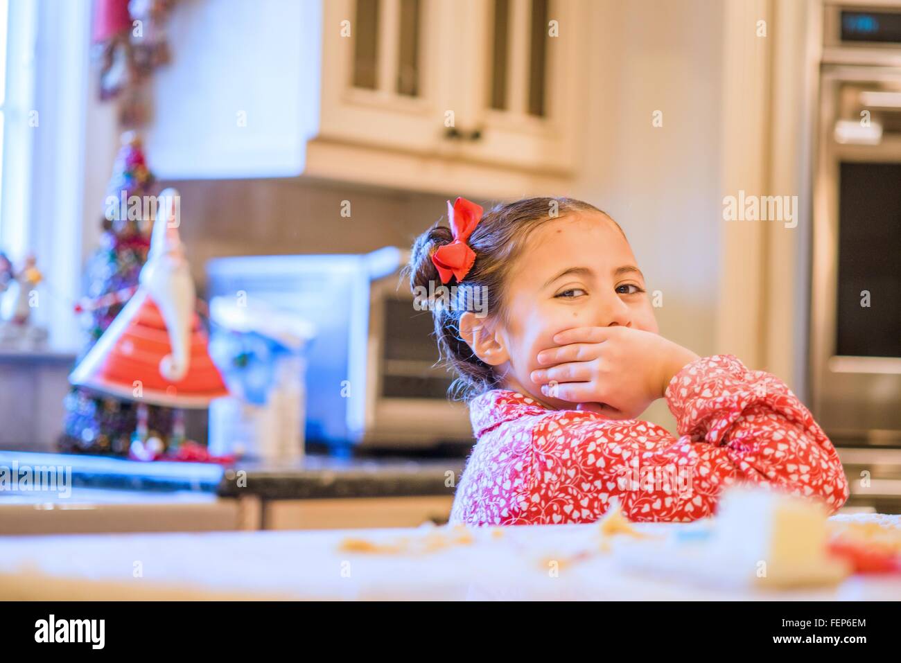 Ritratto di una ragazza con la mano che copre la bocca in cucina Foto Stock