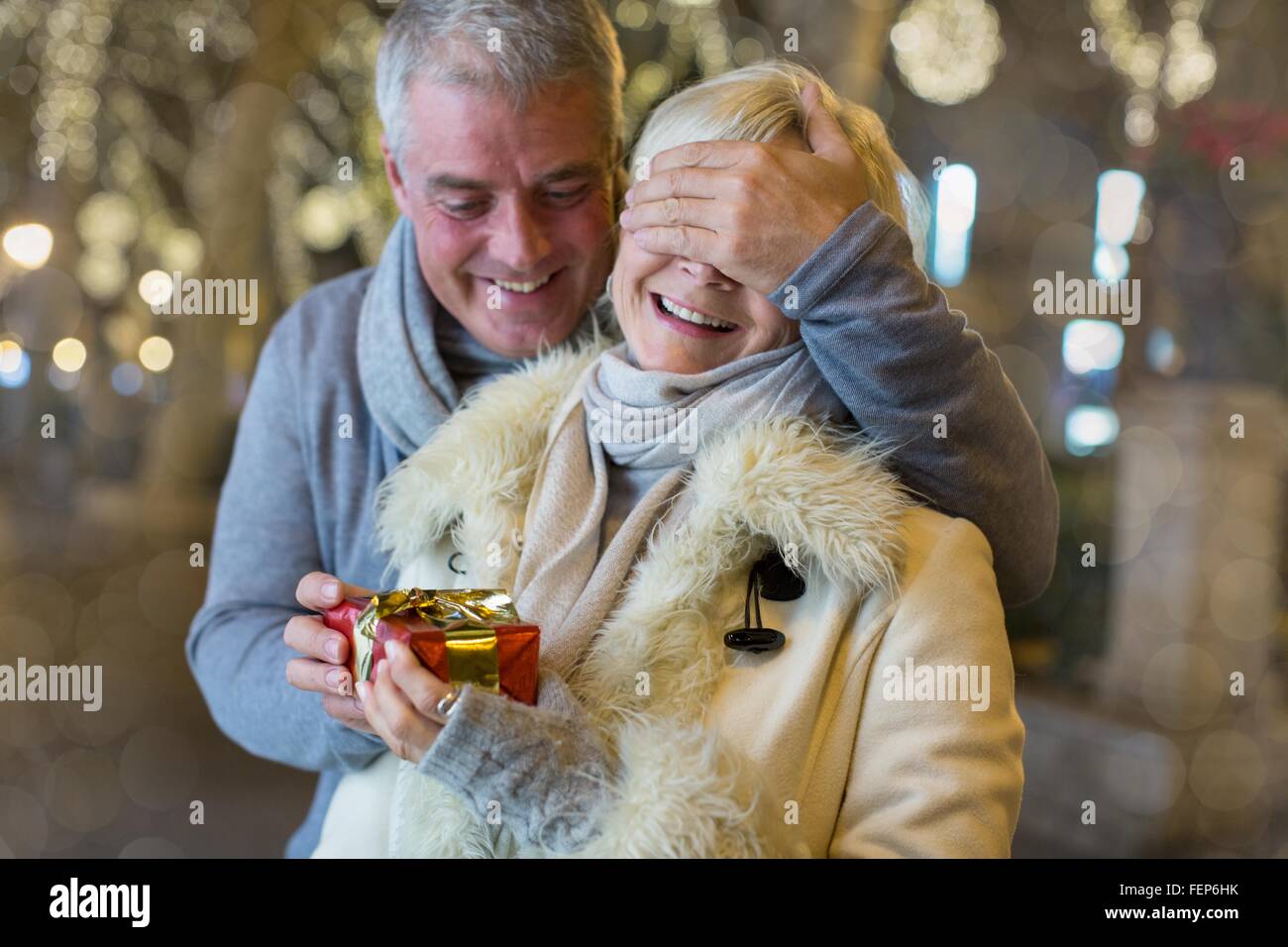 Uomo maturo consegna con il regalo di Natale alla moglie sul viale alberato, Maiorca, SPAGNA Foto Stock