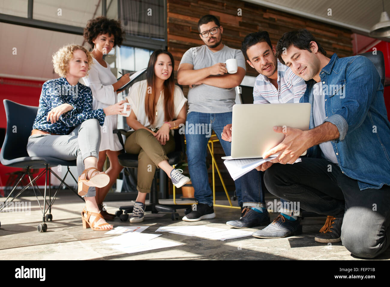 Avvio del lavoro di squadra e la pianificazione in riunione. Un gruppo di giovani uomini e donne guardando il portatile in ufficio. Foto Stock