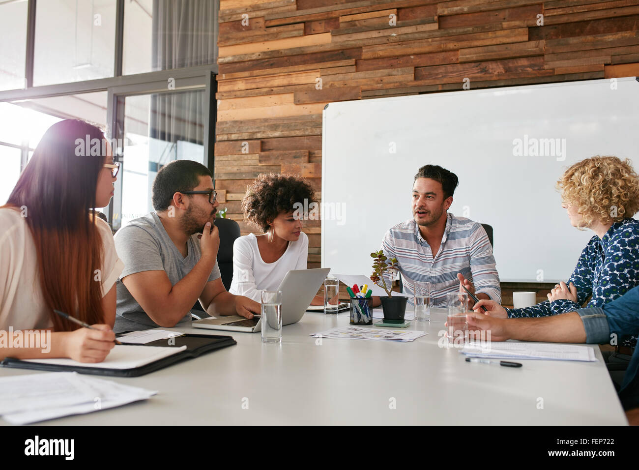 Inquadratura di un gruppo di giovani professionisti di aziende aventi una riunione nella sala riunioni. Gli impiegati a discutere di nuovo business plan toget Foto Stock