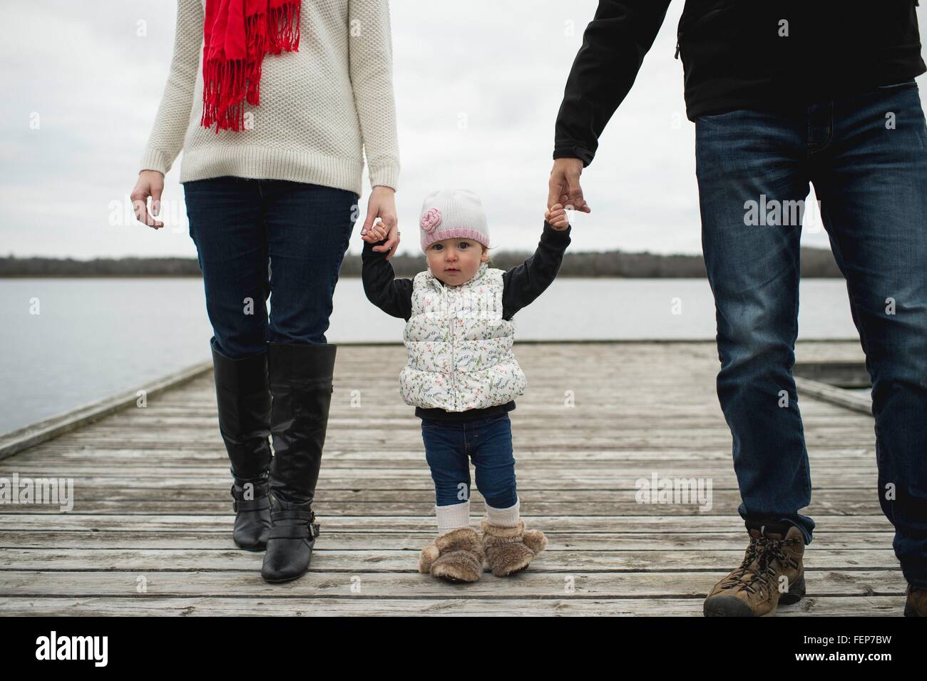 Famiglia giovane, tenendo le mani, camminando sul molo, sezione bassa Foto Stock