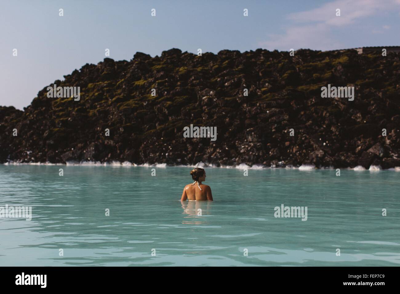 Vista posteriore della metà donna adulta Waist Deep in acqua, Laguna Blu hot springs, Islanda Foto Stock