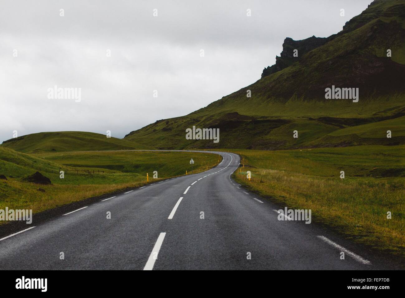 Diminuzione prospettiva della strada aperta dalla rigogliosa montagna verde, Islanda Foto Stock