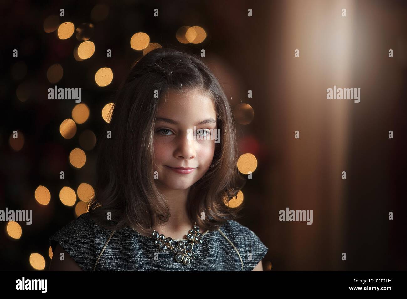 Ritratto di ragazza di fronte di albero di natale guardando sorridente della fotocamera Foto Stock