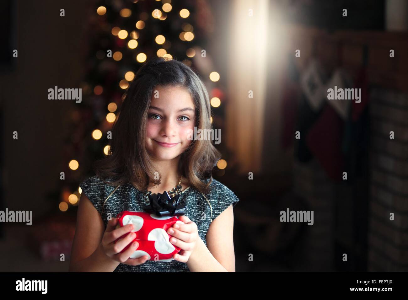 Ritratto di ragazza di fronte di albero di Natale regalo azienda guardando sorridente della fotocamera Foto Stock