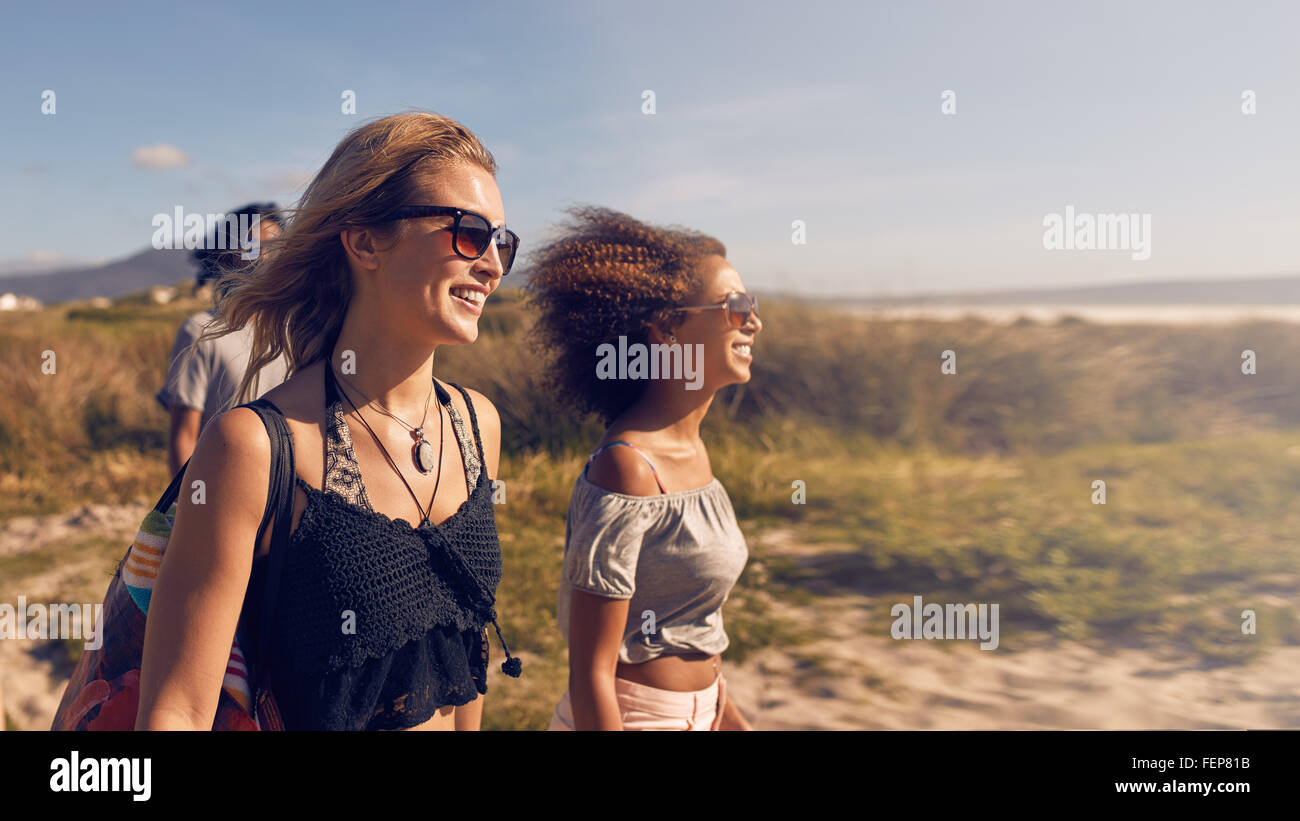 Ritratto di sorridere le giovani donne di andare sulla spiaggia. Amici di sesso femminile sulla riva del mare sul giorno di estate, vacanza in spiaggia. Foto Stock