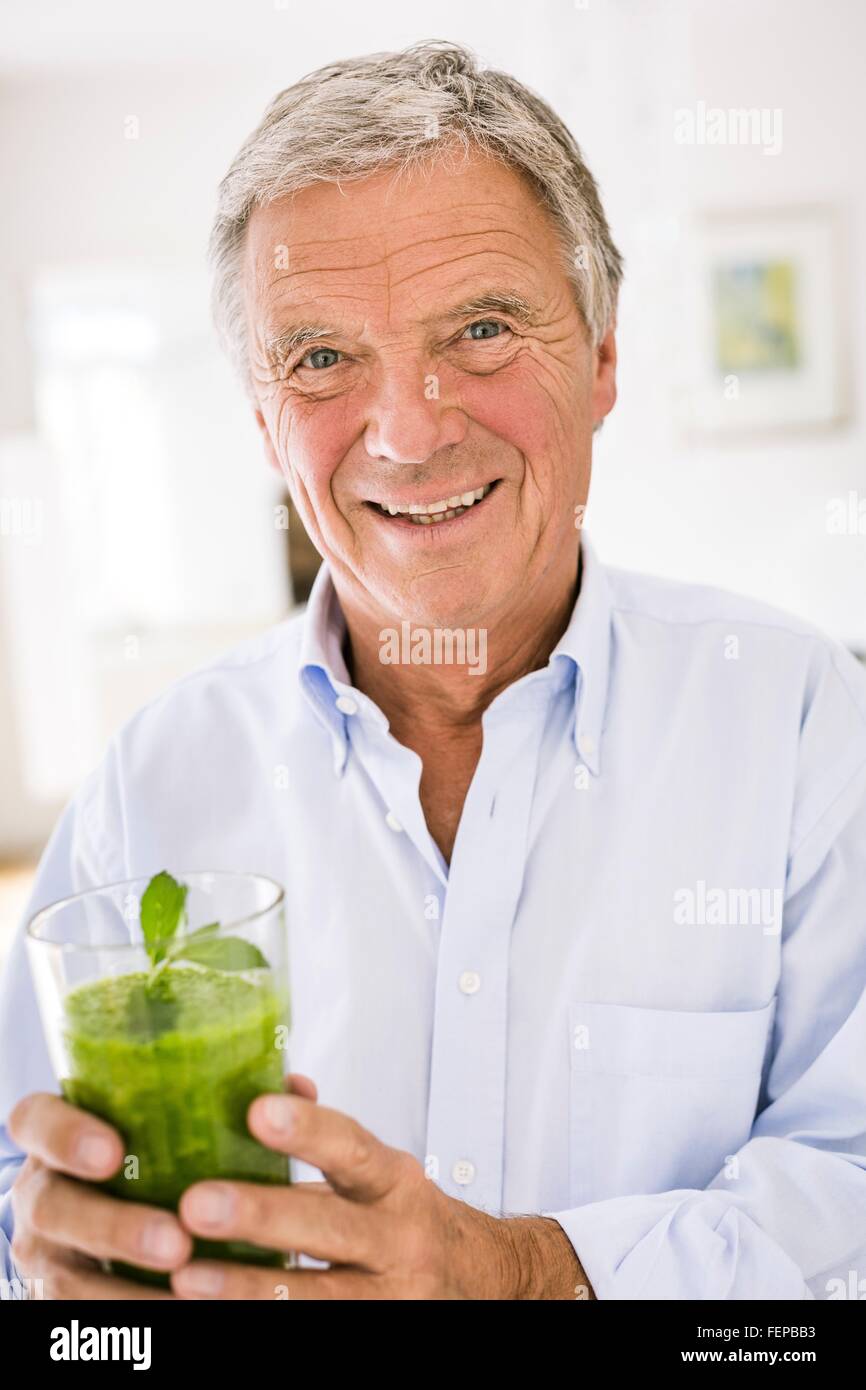 Ritratto di uomo anziano con verde frullato vegetale in cucina Foto Stock
