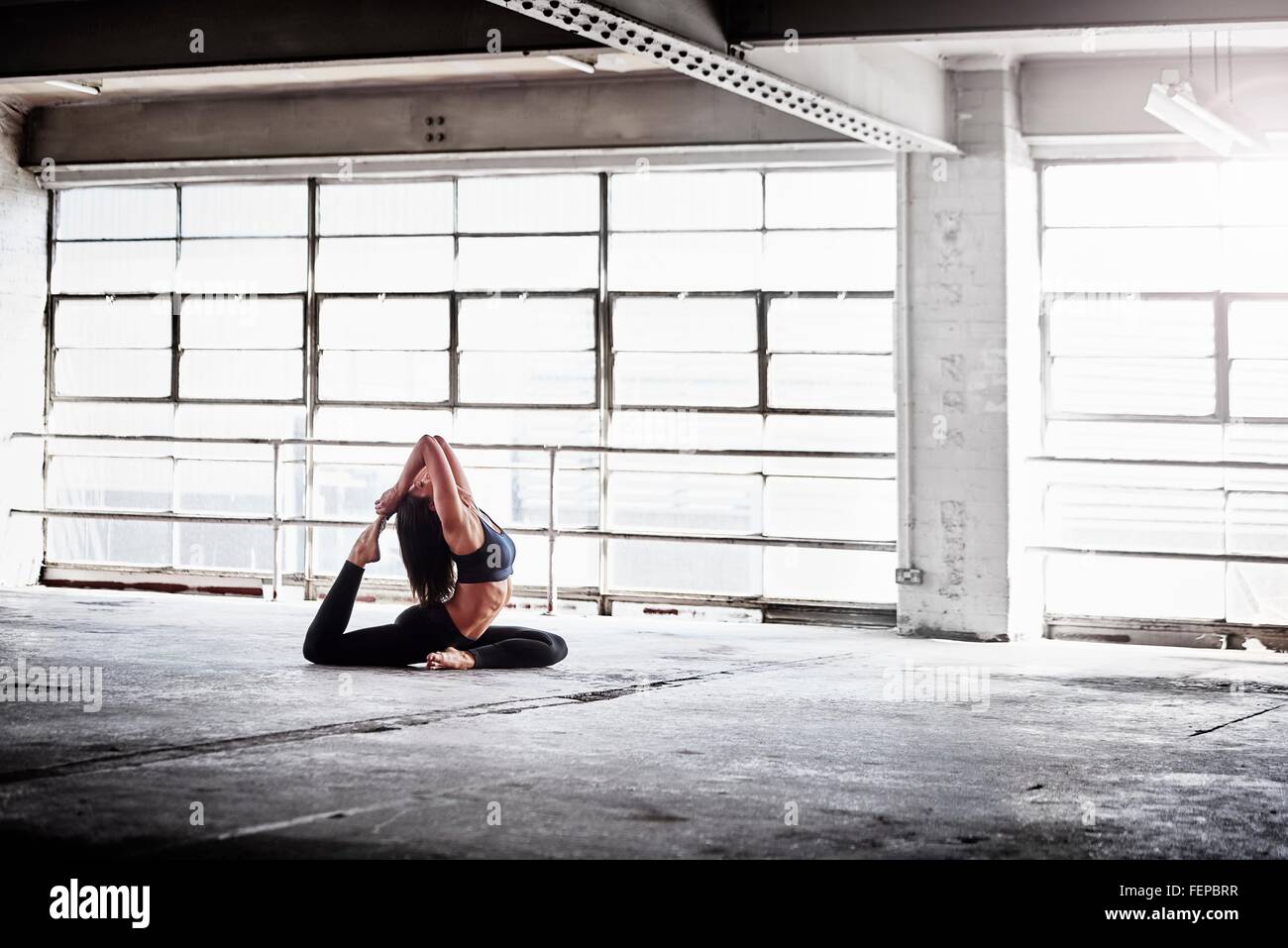 La donna a praticare yoga pone nella parte anteriore della finestra di magazzino Foto Stock