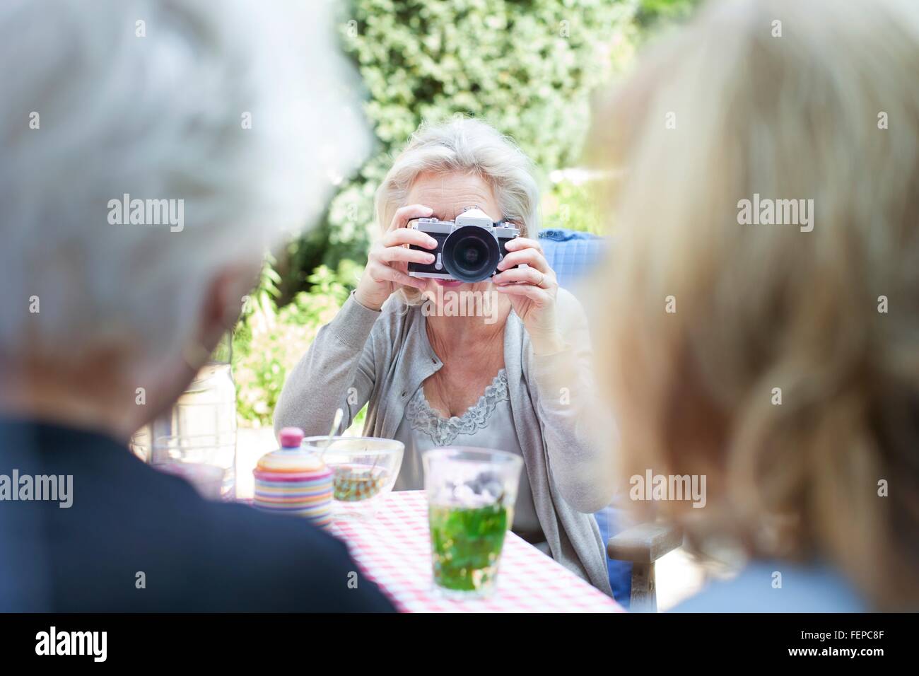 Senior donna assumendo fotografia di amici in giardino Foto Stock