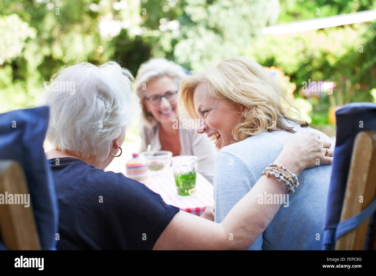 Tre donne insieme rilassante nel giardino, ridendo Foto Stock