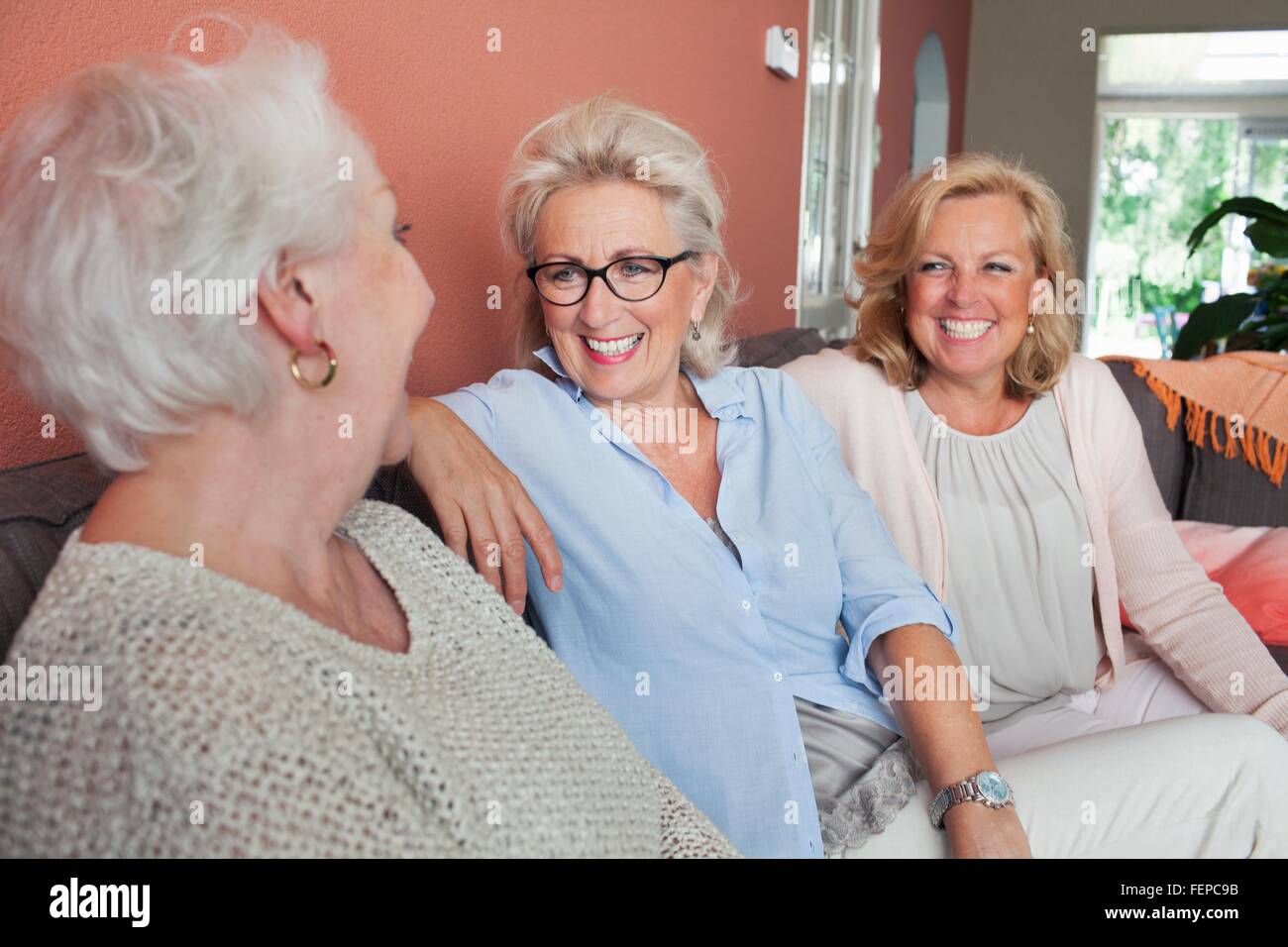 Tre donne seduti sul divano, rilassante, ridendo Foto Stock