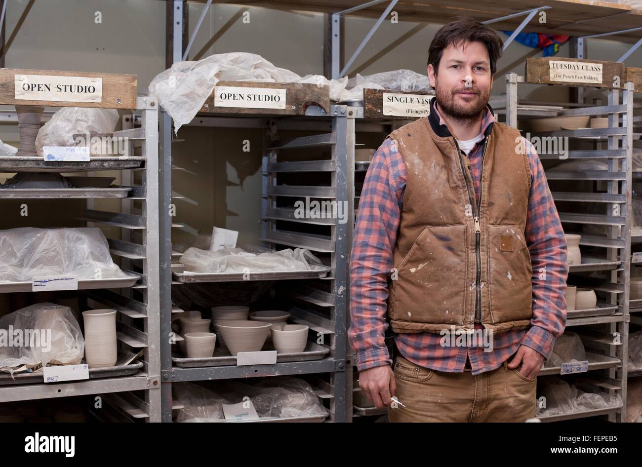 Potter in deposito, una mano in tasca cercando in telecamera sorridente Foto Stock