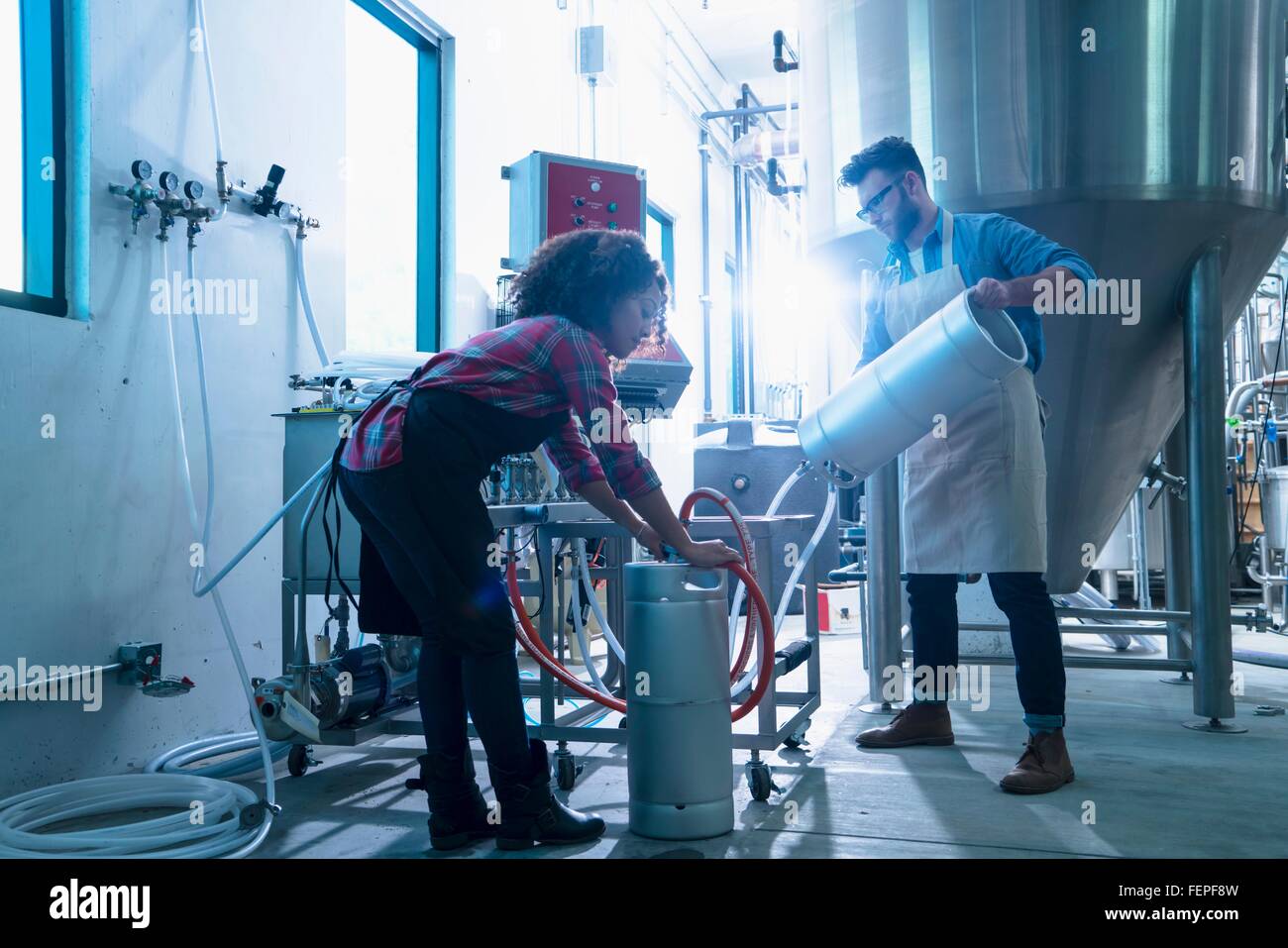 I colleghi nella fabbrica di birra da conica serbatoio di fermentazione di collegare tubo flessibile per taniche Foto Stock