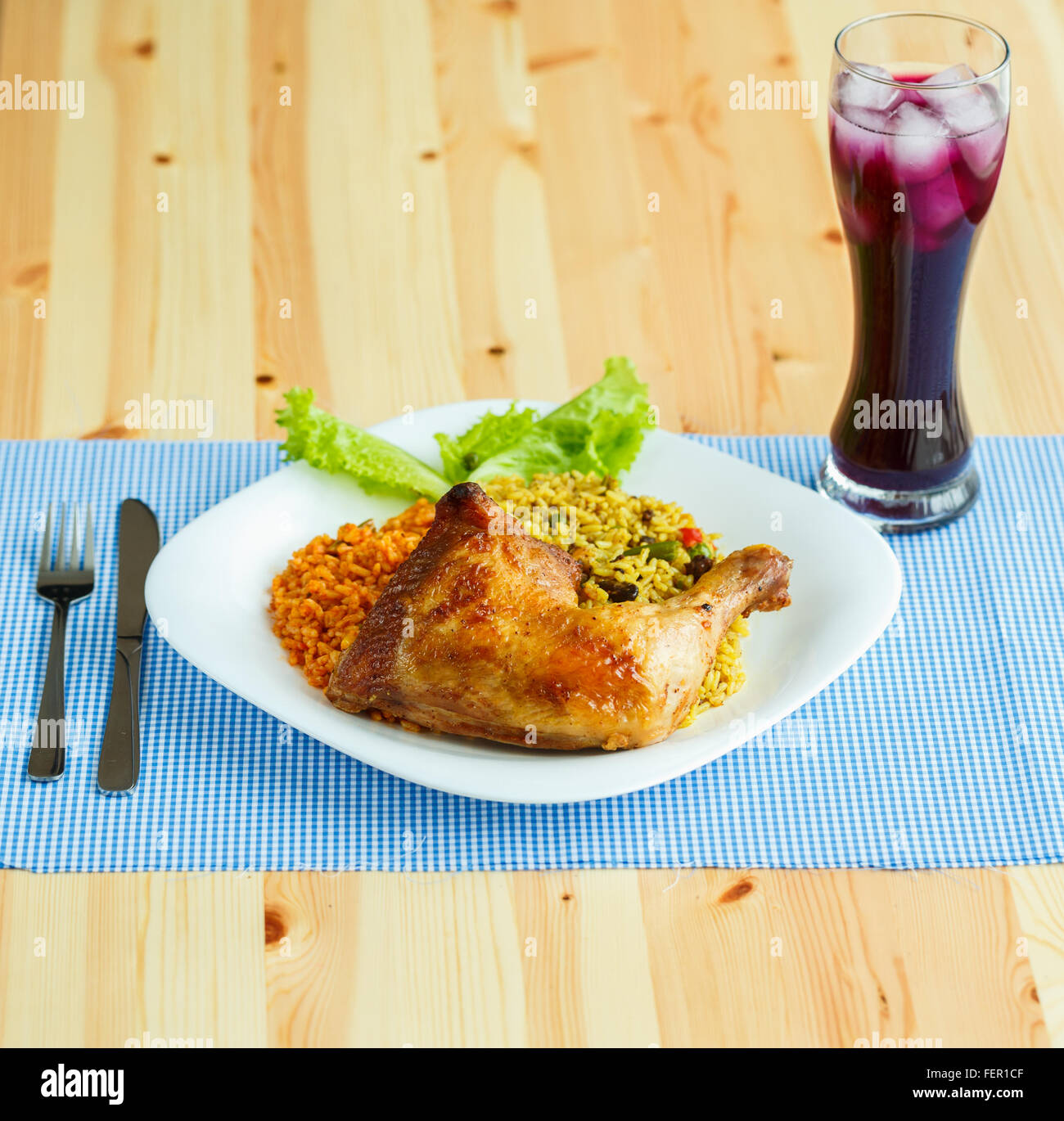 Piatti deliziosi da coscia di pollo con riso e lattuga e un bicchiere di succo di frutta con ghiaccio Foto Stock