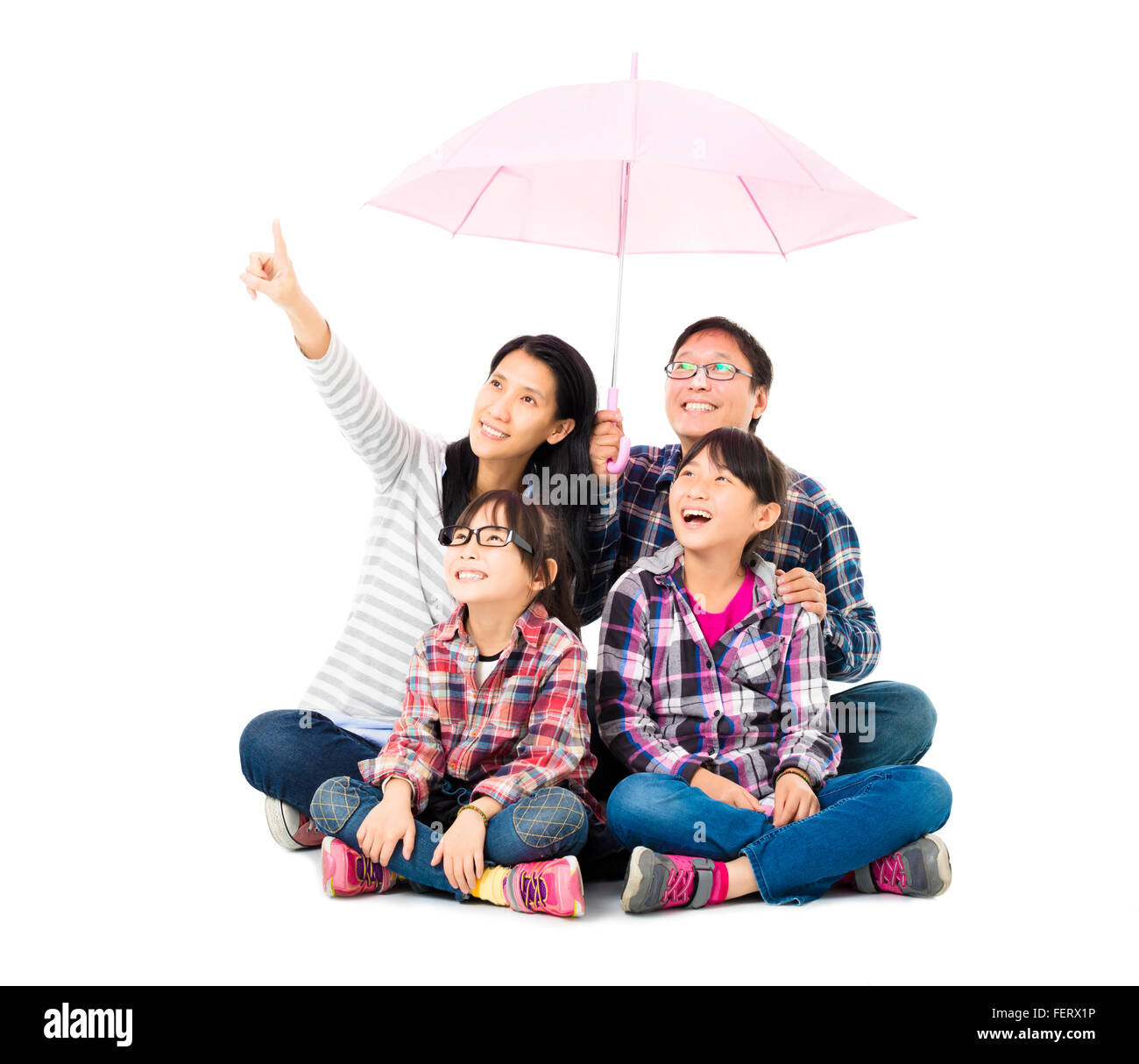 La famiglia felice seduto sotto un ombrello Foto Stock