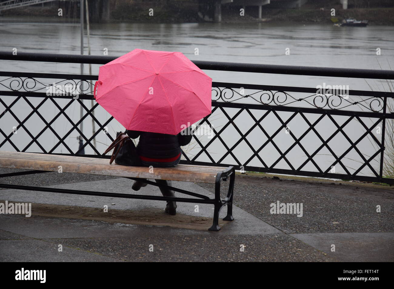 Donna seduta sotto la pioggia. Foto Stock