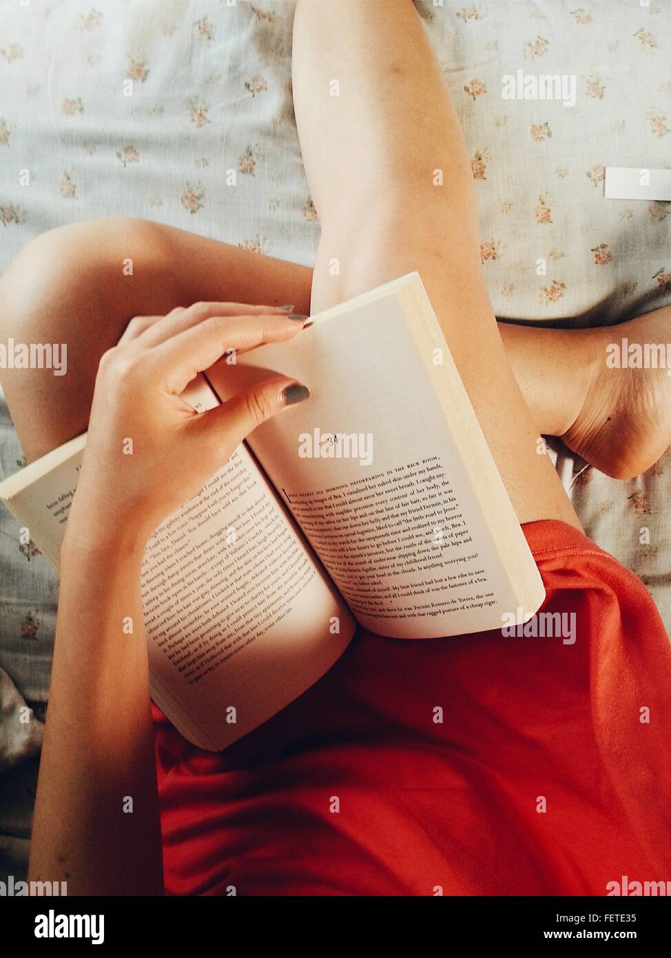 Sezione mediana della donna la lettura di romanzo su letto di casa Foto Stock