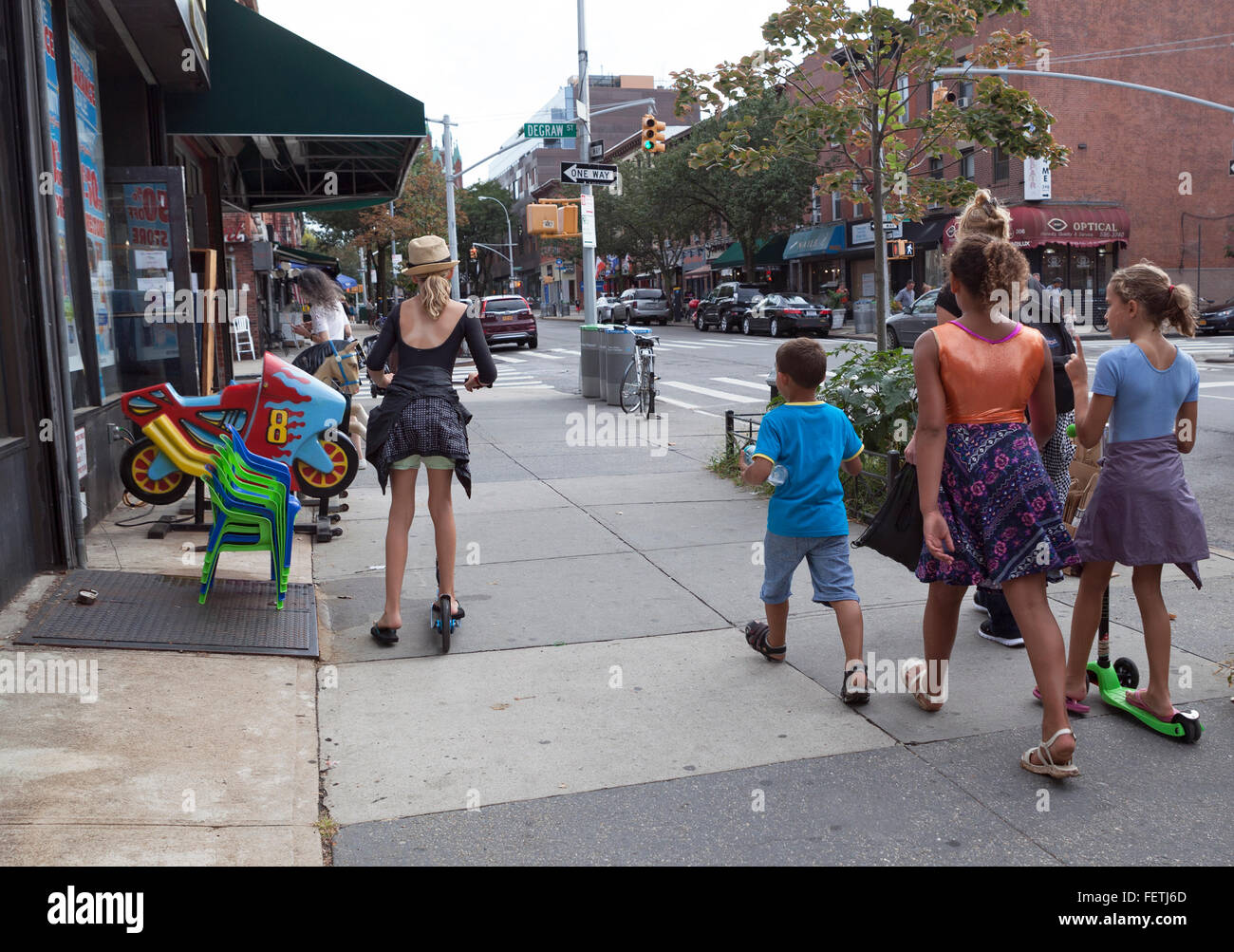 I bambini camminano e usano gli scooter sul marciapiede di Brooklyn, New York, USA. Foto Stock
