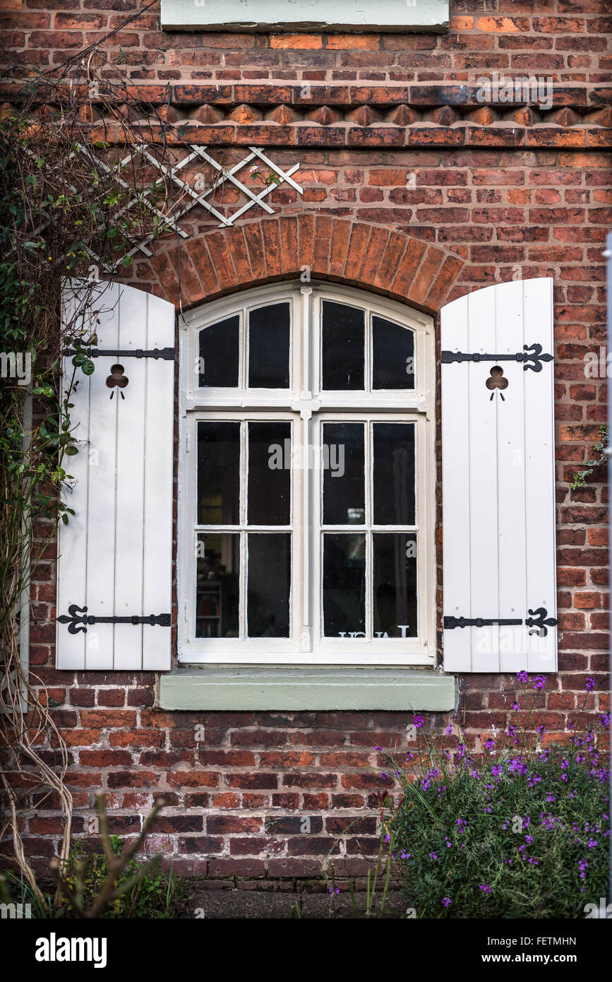 Mattone rosso cottage con persiane di legno e giardino anteriore. Foto Stock
