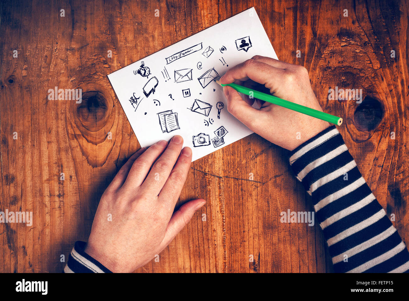 Femmina di graphic designer delineando le icone del software su carta, vista dall'alto, dai toni rétro. Foto Stock