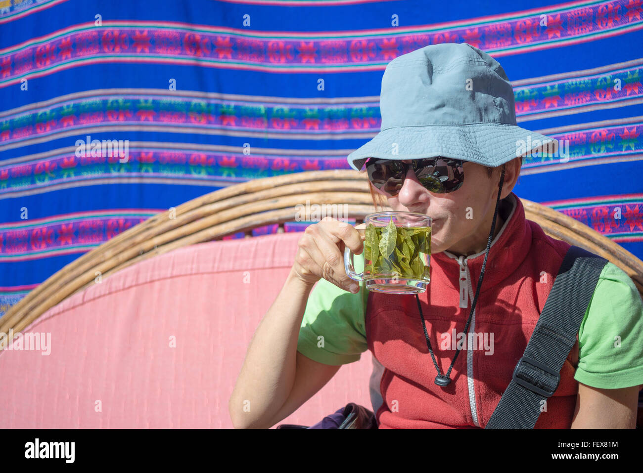 Signora con occhiali da sole e cappello avente una tazza di foglie di coca tea noto come 'Mate de coca', tipica bevanda calda di persone locali lasciando Foto Stock