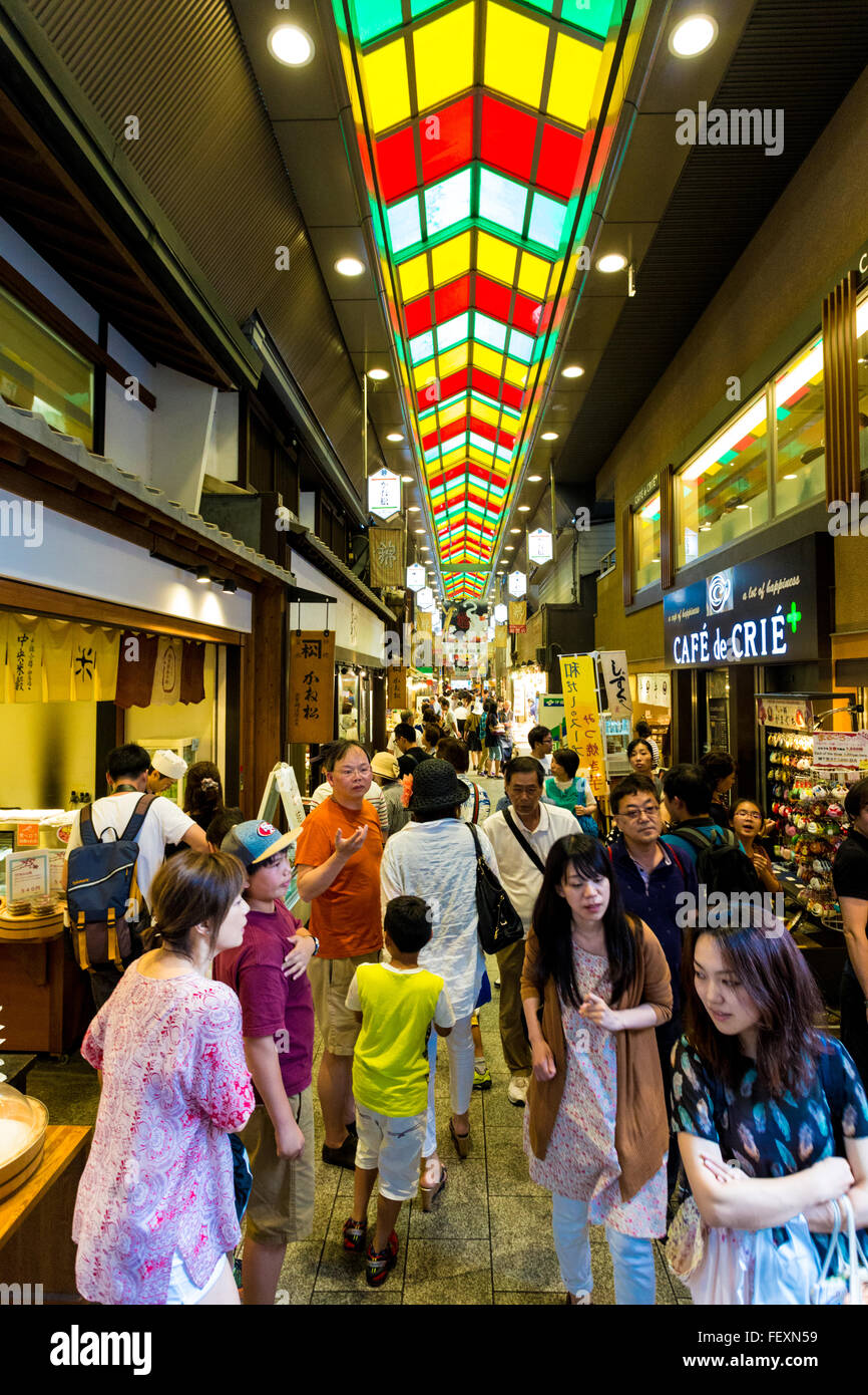 I turisti e i locali a piedi la lunghezza del famoso indoor mercato Nishiki chioschi e ristoranti lungo i lati di un lon Foto Stock