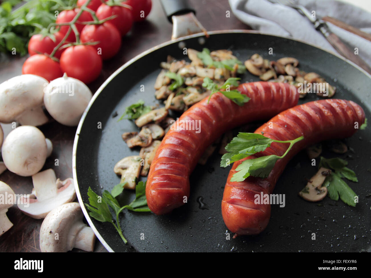 Padella calda con salsicce alla griglia e funghi con prezzemolo Foto Stock